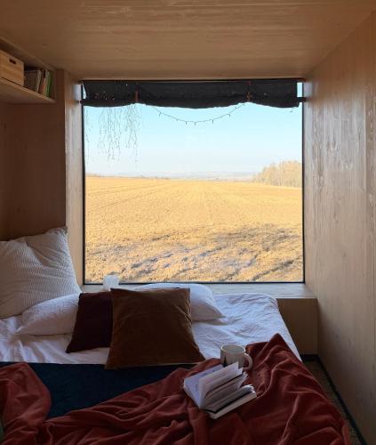 a bed in a room with a view of a field at Ostrov klidu - posed - sauna in Hradešín