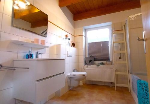 a bathroom with a toilet and a sink and a shower at Ferienhaus Dea in Krummhörn