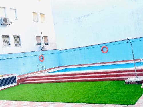 a building with a wall with a bench and grass at Apartamento Terraza a la Almadraba in Barbate