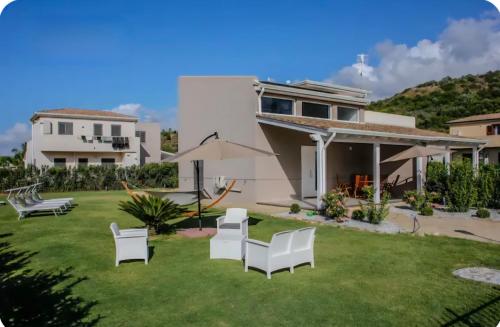 a house with a yard with white chairs at Villa Charme & Relax in Campofelice di Roccella