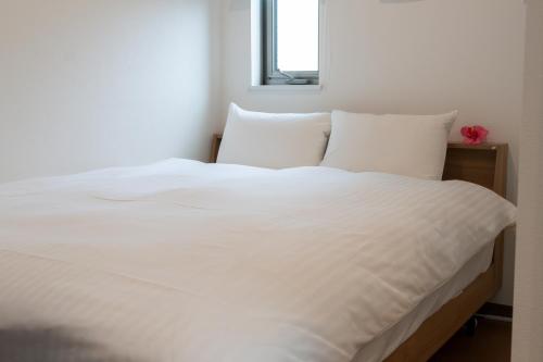a white bed with white sheets and pillows at Kag R大濠1 in Fukuoka
