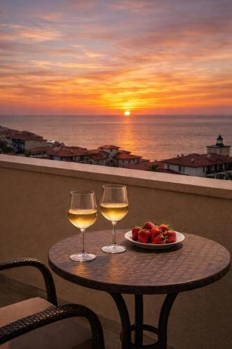 a table with two glasses of wine and a plate of fruit at Sea Vista Hotel in Sveti Vlas