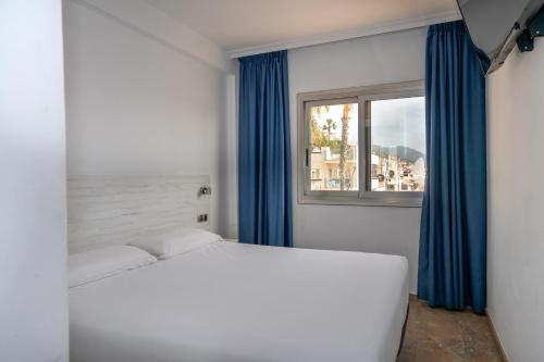 a bedroom with a white bed and a window at Hotel Port Sitges in Sitges