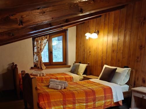 a bedroom with two beds and a window and wooden walls at Residence Les Myosotis in Champoluc