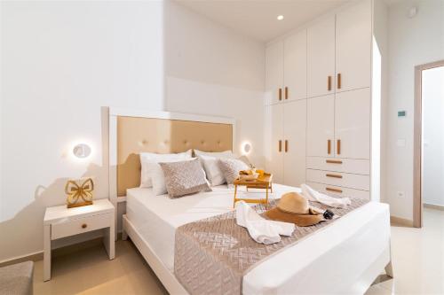 a white bedroom with a large bed with a hat on it at Nerida Luxury Villas in Kastéllion