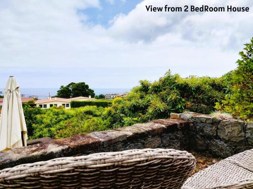 a view of a patio with an umbrella and a stone wall at Moinho&Casa do Tareco in Biscoitos