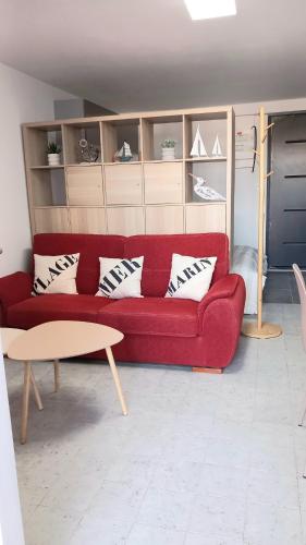 a red couch in a living room with a table at Studio cosy proche bourg et plages tout équipé in Plouhinec