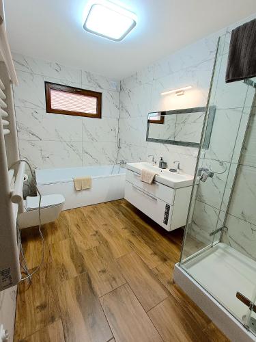 a bathroom with a tub and a sink and a shower at Willa Kwiat Jabłoni in Mikołajki
