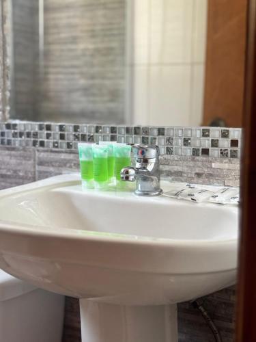 a bathroom sink with two green glasses on it at Linda Vista Apart Hotel in Concón