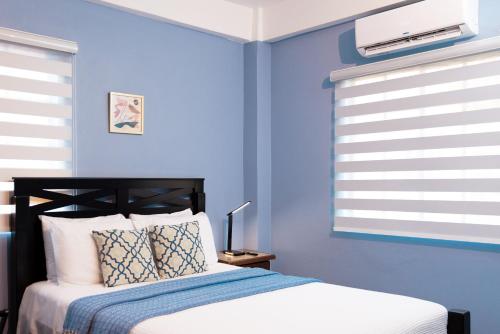 a blue bedroom with a bed with a blue wall at Ahra Suites First Floor with ocean view in Kingstown