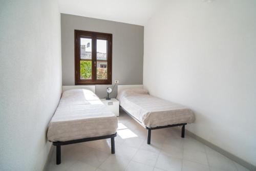 two twin beds in a room with a window at La Cinta Apartments in San Teodoro