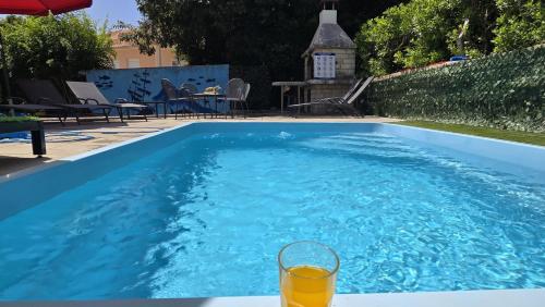 a glass of orange juice sitting on a table next to a swimming pool at CENTRO POOL House in Novalja
