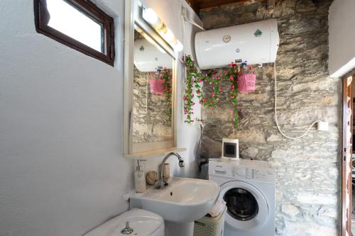 a bathroom with a sink and a washing machine at Manoli's Light Stone House in Vathi