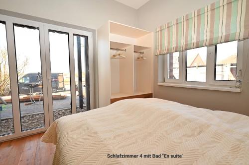 a bedroom with a bed and windows with a view at Residenz R1 App 5 in Behrensdorf