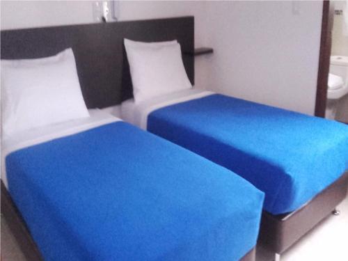 two beds sitting next to each other in a bedroom at Hotel Abadias De Zapatoca in Zapatoca