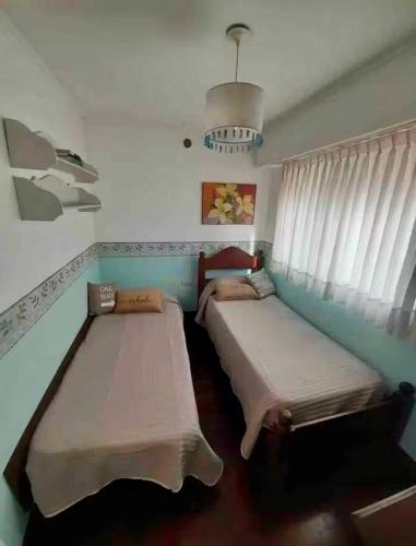 two beds sitting in a room with a window at Casa Colibrí zona Parque Saavedra de La Plata in La Plata