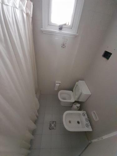 a white bathroom with a toilet and a window at Casa Colibrí zona Parque Saavedra de La Plata in La Plata