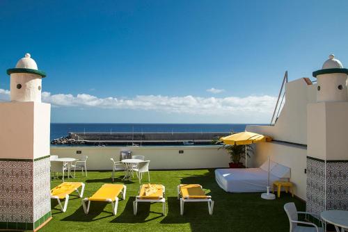 a balcony with chairs and a bed and a table at Apartamentos Tapahuga in Playa de Santiago