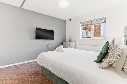 a bedroom with a white bed and a flat screen tv at Hayy Studios at Castleford in Castleford