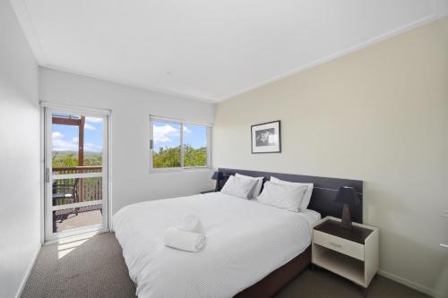ein Schlafzimmer mit einem weißen Bett und einem Fenster in der Unterkunft Beachfront Family Apt - Ocean Views in Diamond Beach