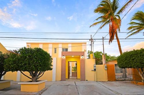 a yellow house with a yellow door and a palm tree at Poolside Retreat Lounge Parking Near Downtown in La Paz