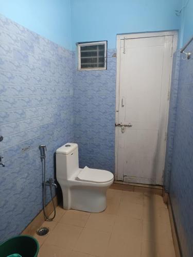 a bathroom with a white toilet in a blue room at Patkai Backpackers Hostel in Guwahati