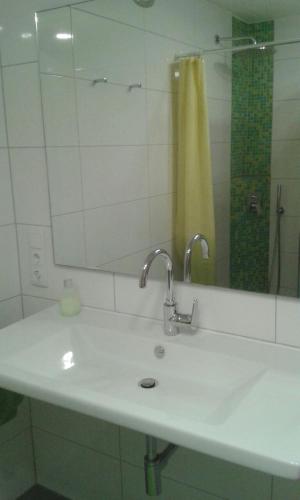 a bathroom sink with a mirror and a yellow shower curtain at Ferienwohnung Wiesengrund in Überlingen