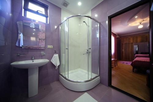 a bathroom with a glass shower and a sink at Hotel Harmony in Kutaisi