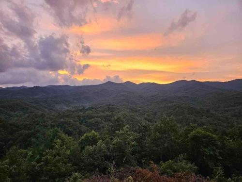 a sunset over a forest with mountains in the background at Sky Harbour in Andrews