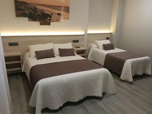 a room with two beds with white and brown at Pensión Plaza in Quintáns