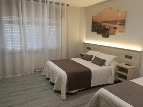 a bedroom with two beds and a window at Pensión Plaza in Quintáns