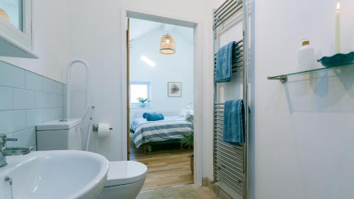 a white bathroom with a sink and a toilet at Pen Bonc in Moelfre