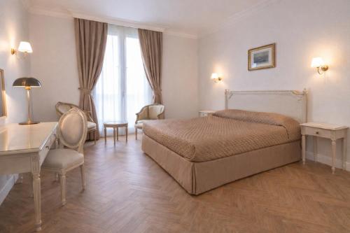 a bedroom with a bed and a table and chairs at Grand Hôtel Moderne in Lourdes