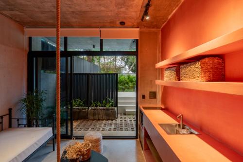 a room with an orange wall and a sink at The Surfer's Base in Jacó