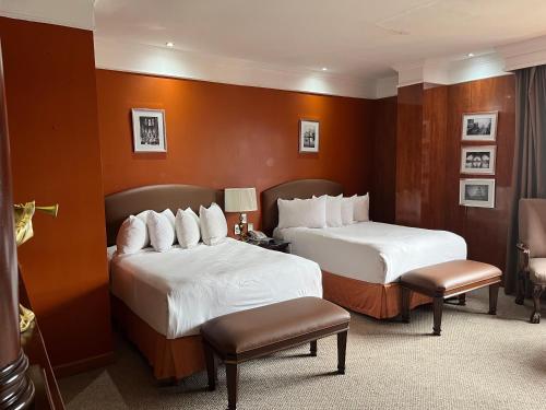 two beds in a hotel room with two chairs at Hotel Real de Don Juan in Tepic