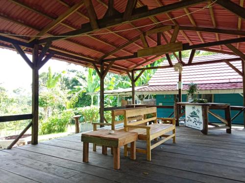 a wooden deck with a bench and a table at The Ridge Surf Lodge in Biha