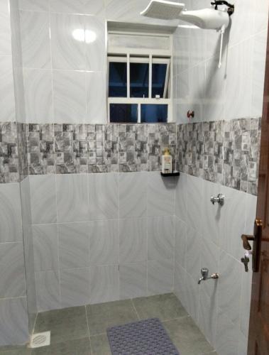 a bathroom with a shower with gray and white tiles at Urbanza Haven Nakuru in Nakuru