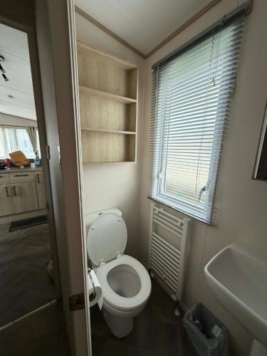 a bathroom with a toilet and a sink and a window at 6 berth caravan in Ingoldmells opposite beach in Ingoldmells