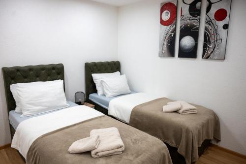 two beds in a room with towels on them at Apartmani Prestige in Gornji Vakuf