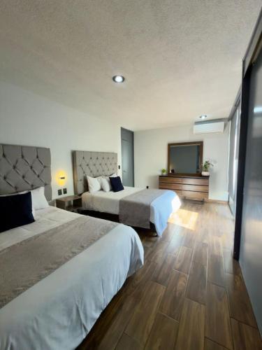a hotel room with two beds and a flat screen tv at AR Suites 3 La Calzada in Zamora de Hidalgo