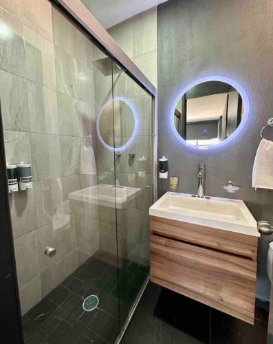 a bathroom with a sink and a shower with a mirror at AR Suites 2 La Calzada in Zamora de Hidalgo