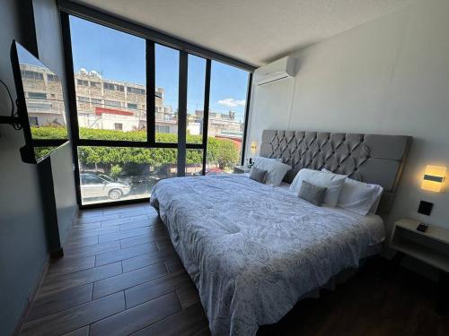 a bedroom with a large bed and a large window at AR Suites 2 La Calzada in Zamora de Hidalgo