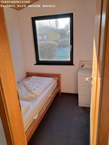 a small bedroom with a bed and a window at Wald Chalet Nr 4 in Kellenhusen
