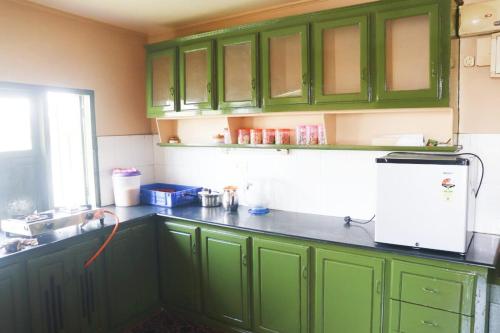 a kitchen with green cabinets and a white refrigerator at Sacred River Houseboats in Alleppey