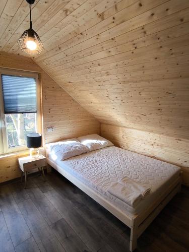ein Schlafzimmer mit einem Bett in einem Holzzimmer in der Unterkunft Cicha Przystań Skępe 300 m od jeziora in Skępe