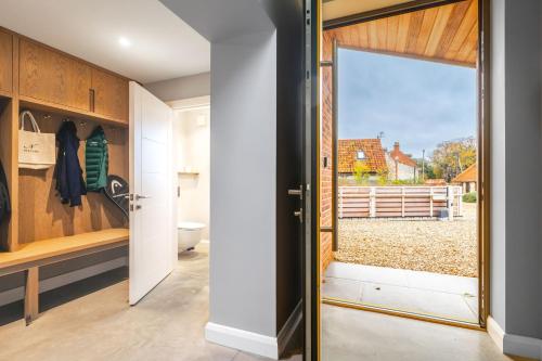 a pivot door opens up to a bathroom with a window at Seahenge in Brancaster
