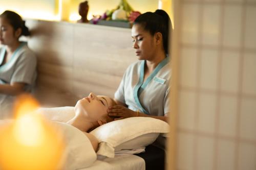 a woman in a massage room with a therapist at The Snowbell Hotel & Spa at The Bridge in Phnom Penh