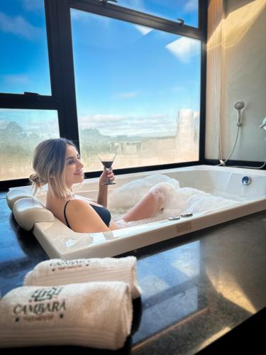 a woman sitting in a bath tub with a glass of wine at Tiny House Cambará in Cambará