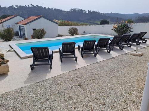 a group of chairs sitting in front of a swimming pool at VillaVie CostadePrata in Alfeizerão