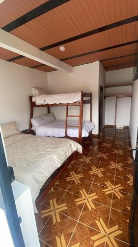 two beds in a room with a tiled floor at Hotel Campestre Kambra in Garagoa